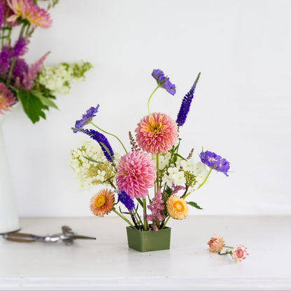Square pin cup flower frog kenzan with brightly colored flowers