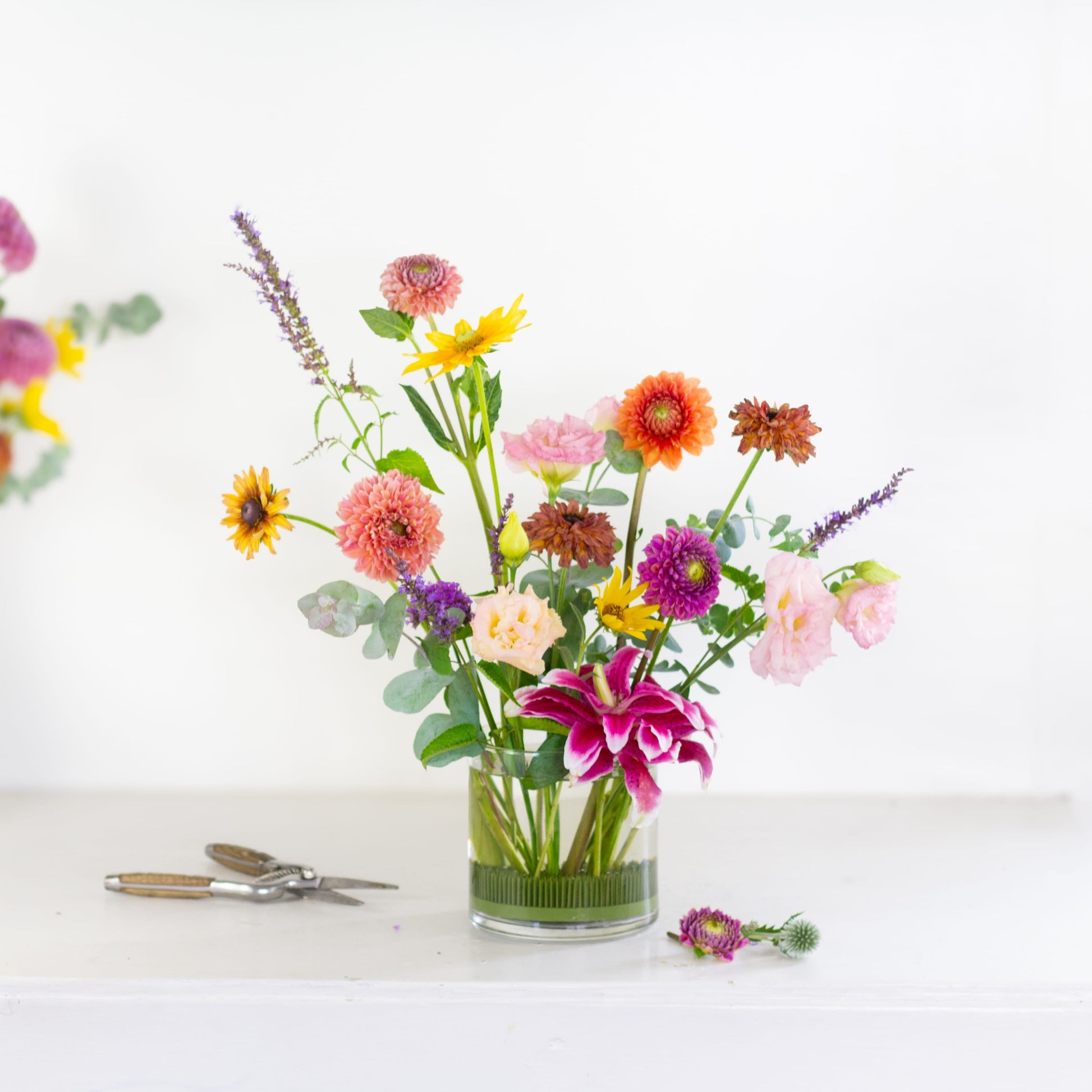 Round kenzan flower frog pin holder with flowers in a glass vase