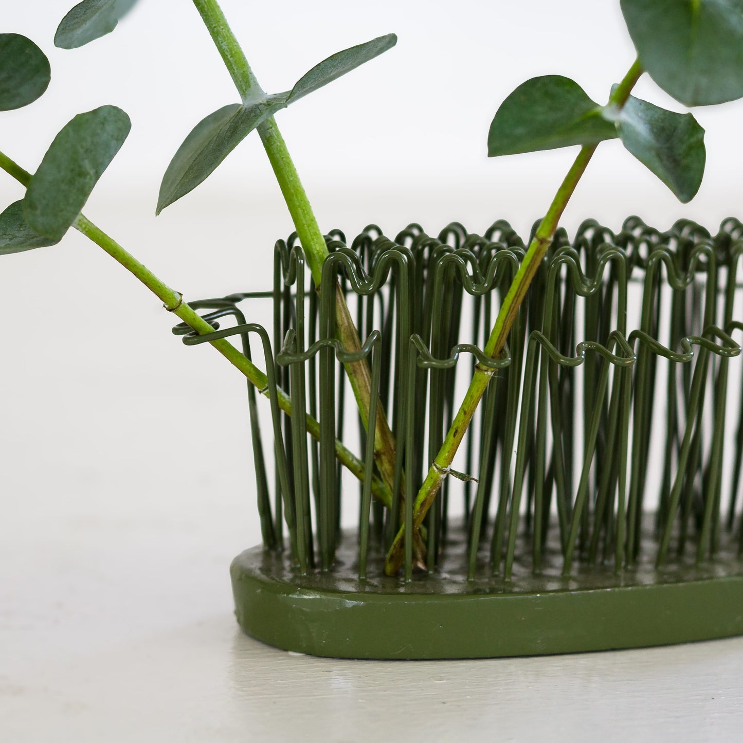 How to use a hairpin holder flower frog with eucalyptus branches inserted.