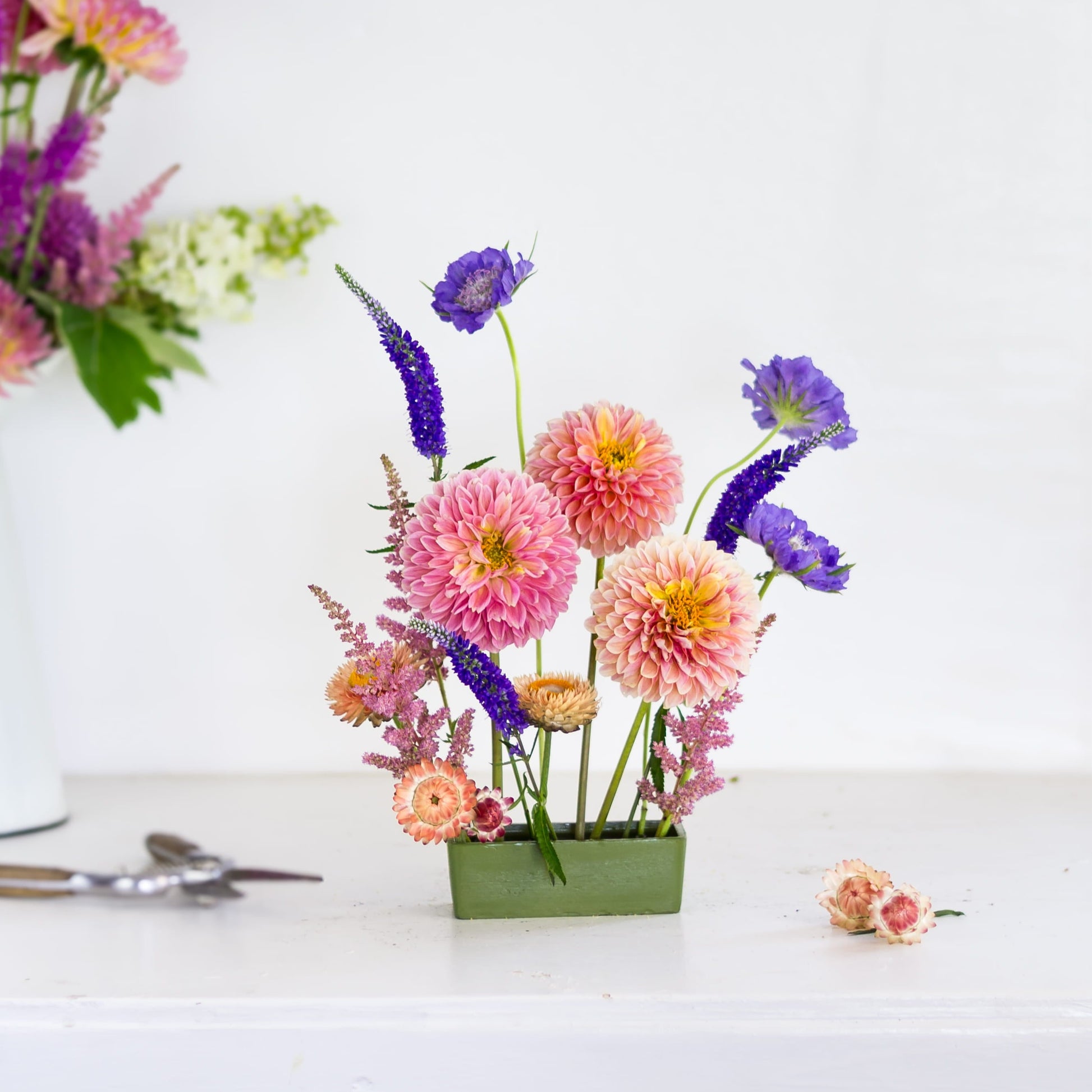 Brightly colored flowers in a rectangle green pin cup flower frog kenzan