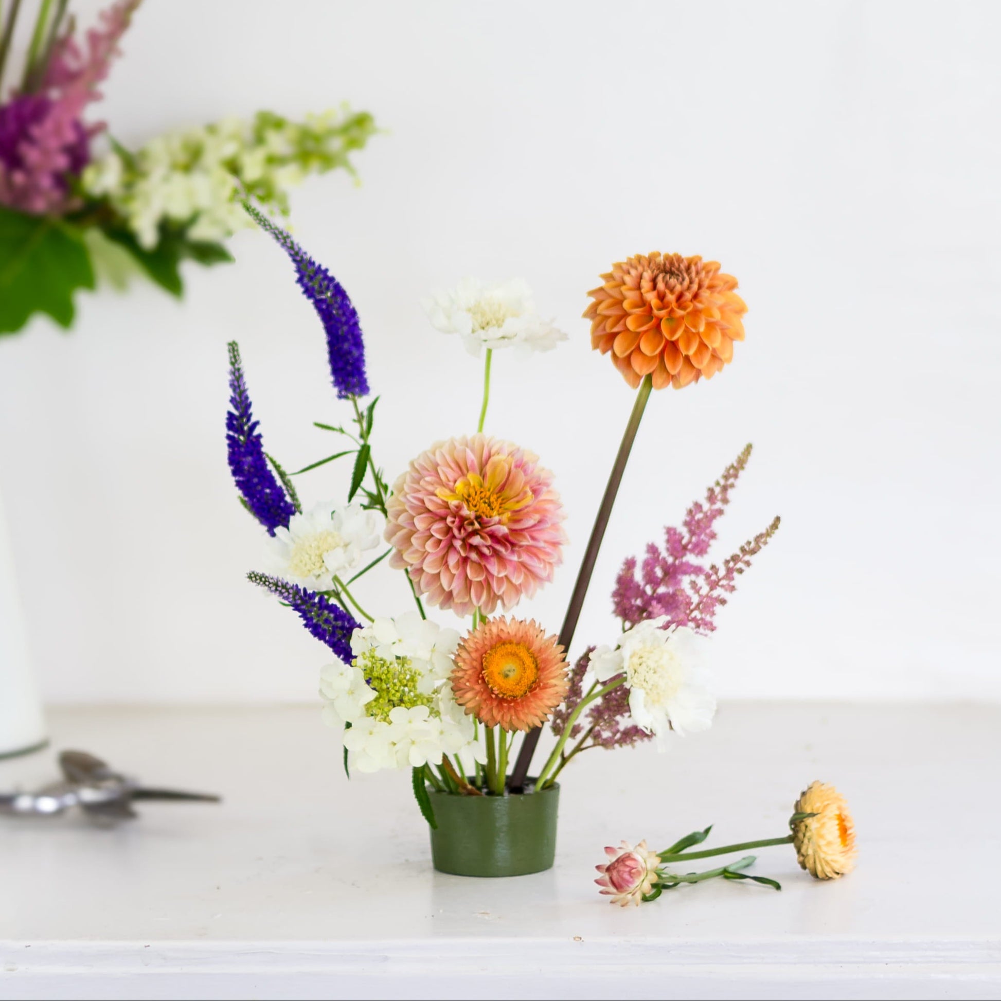 Brightly colored flowers in a green metal pin cup flower frog