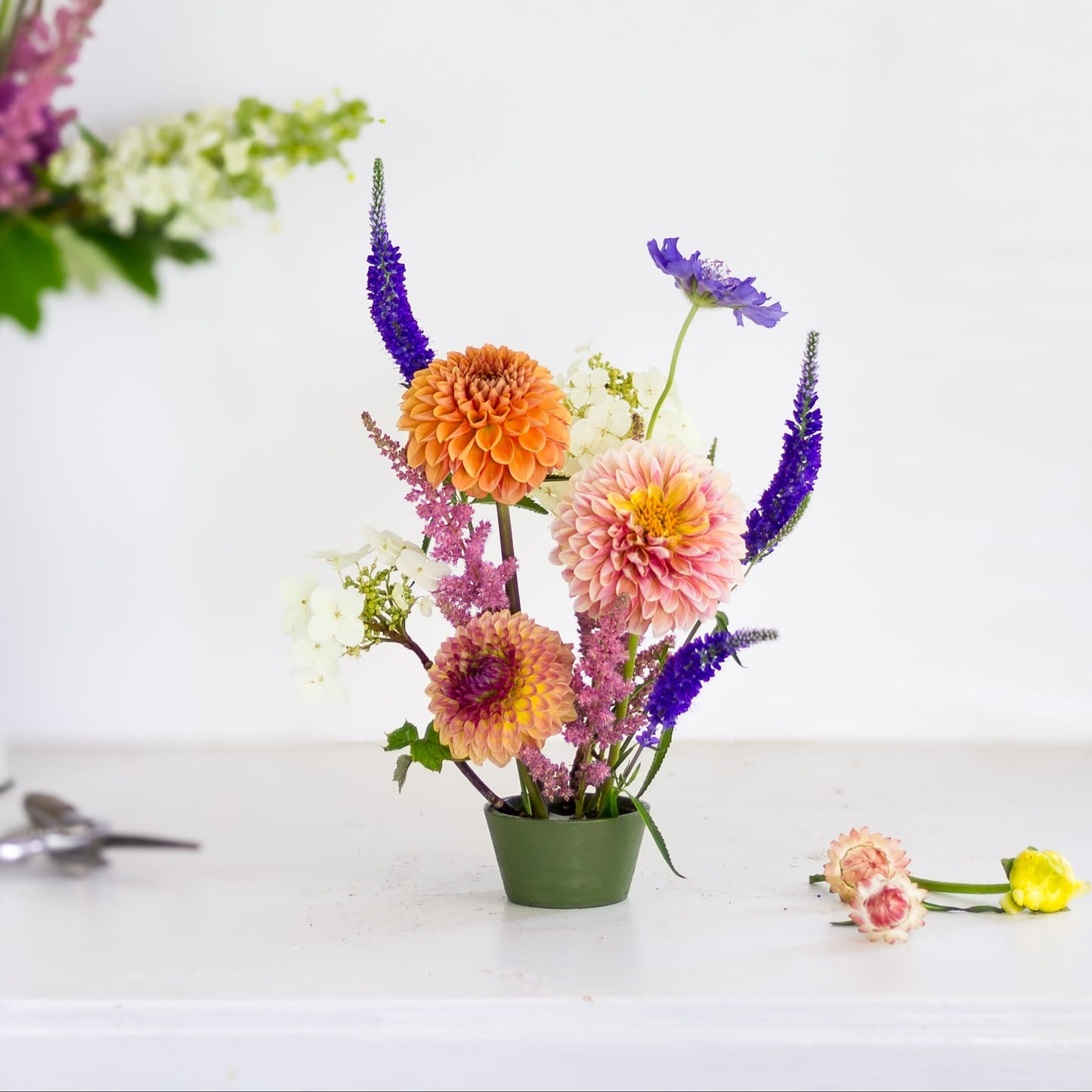 Round green kenzan pin cup with brightly colored flowers 